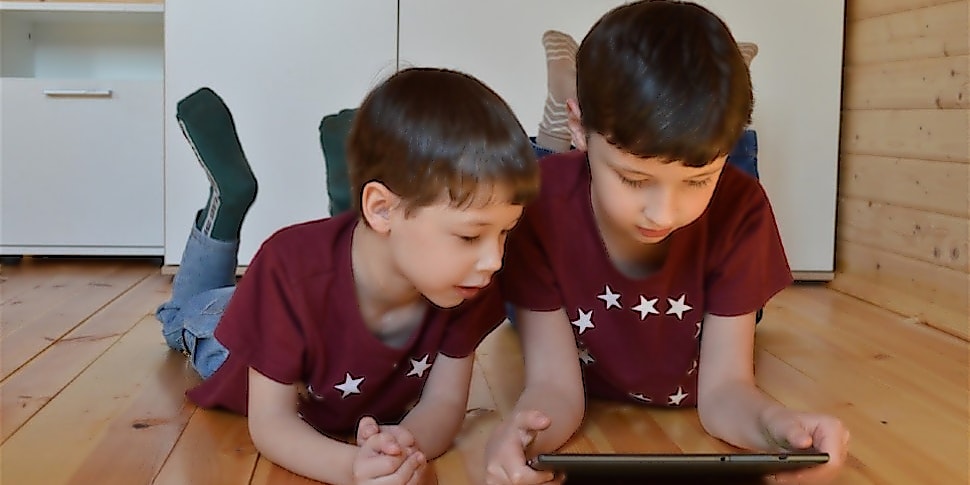 Zwei Kinder liegen auf dem Boden und spielen mit einem Tablet für Kinder