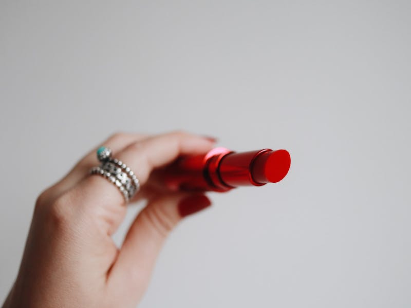 Hand mit Ring hält roten Lippenstift