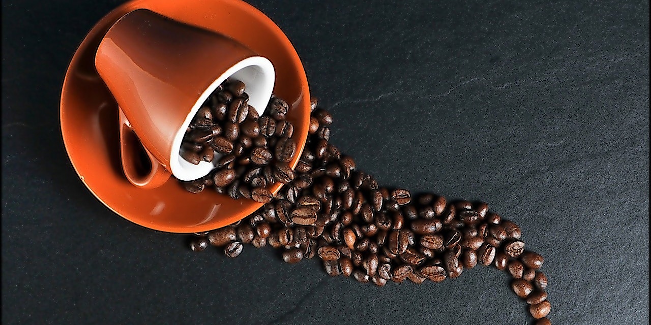 Coffee Friend Gutschein Kaffeetasse voller Kaffeebohnen liegt umgekippt auf Unterteller