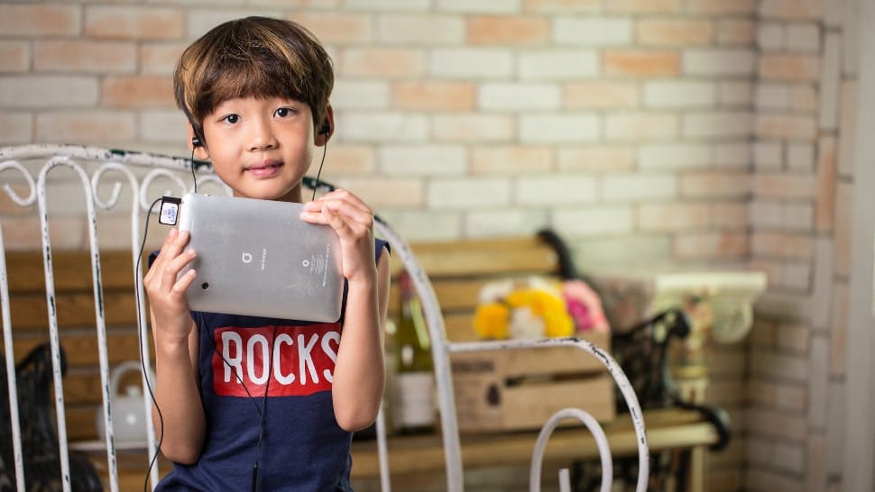 Ein Kind sitzt auf einer Bank und hat ein Tablet für Kinder in seinen Händen