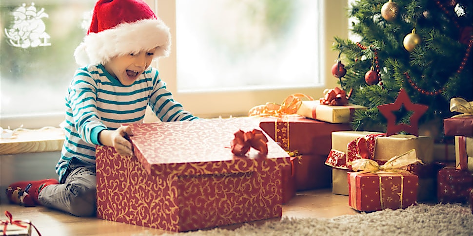 Junge öffnet freudig sein Weihnachtsgeschenk