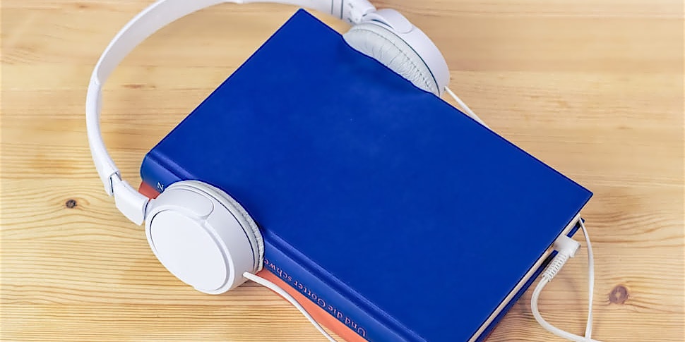 Blaues Buch mit weißen Kopfhörern um den Einband