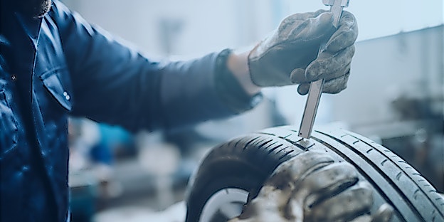 Autoreifen_wechseln_Profiltiefe KfZ-Mechaniker misst die Profiltiefe des Reifens