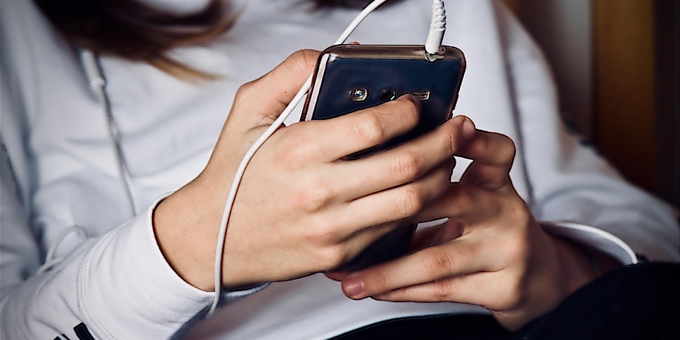 ntv-Hörbuch-Abo-Smartphone Frau hört über Kopfhörer etwas über ihr Smartphone