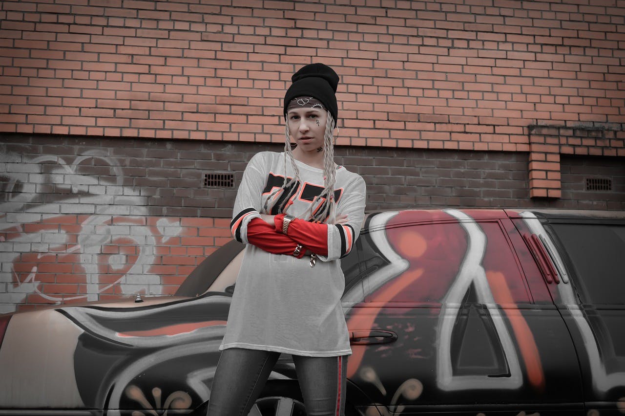 Frau in Streetwear Bekleidung steht vor einer mit Graffiti besprühten Wand