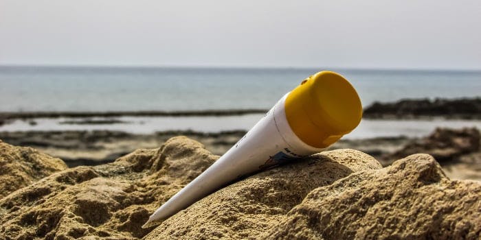 Tube Sonnencreme liegt im Sand am Meer