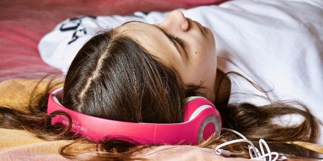 Ein Mädchen liegt und hört etwas mit seinen Kopfhörern