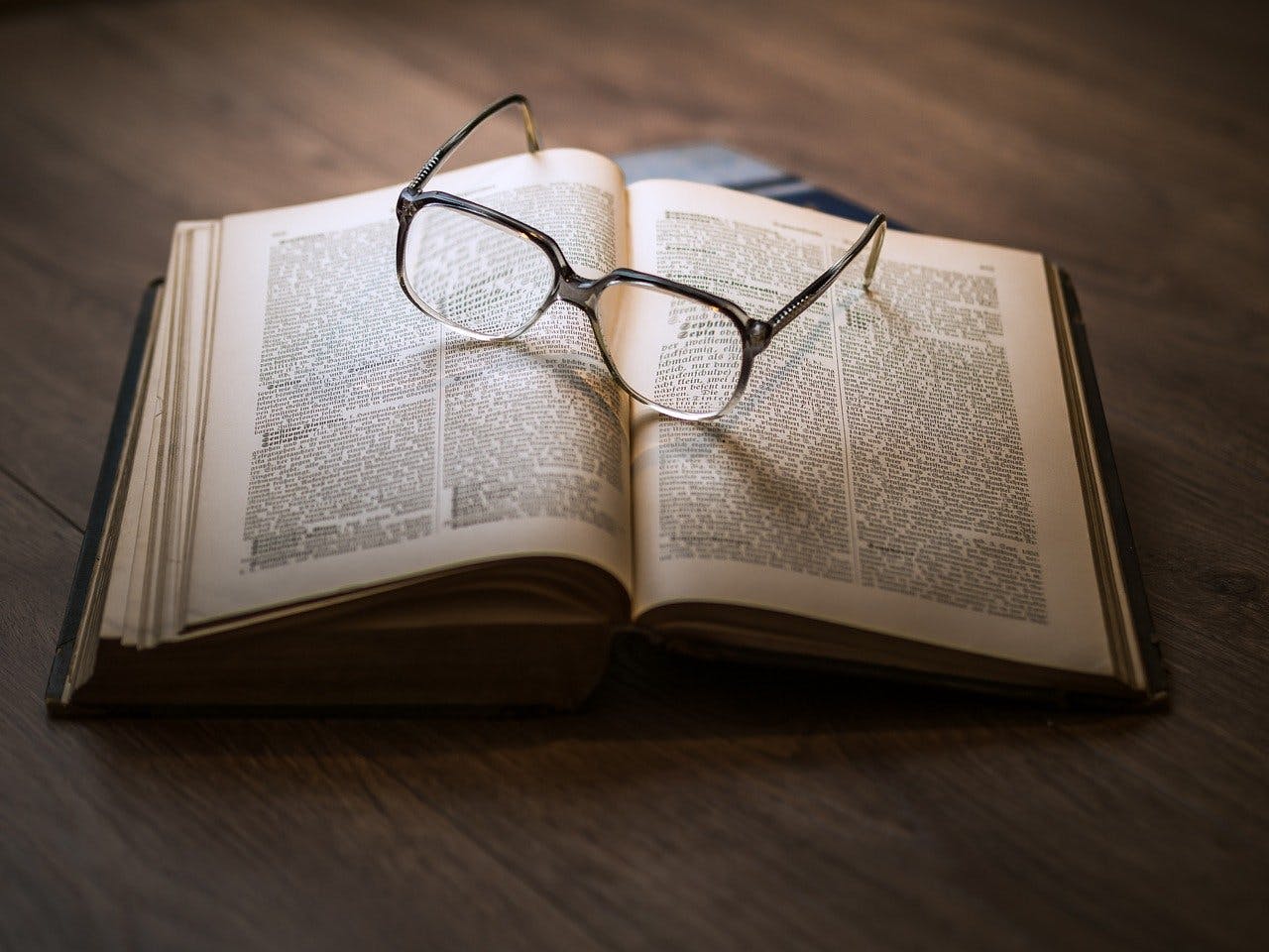 Brille liegt auf aufgeschlagenem Buch