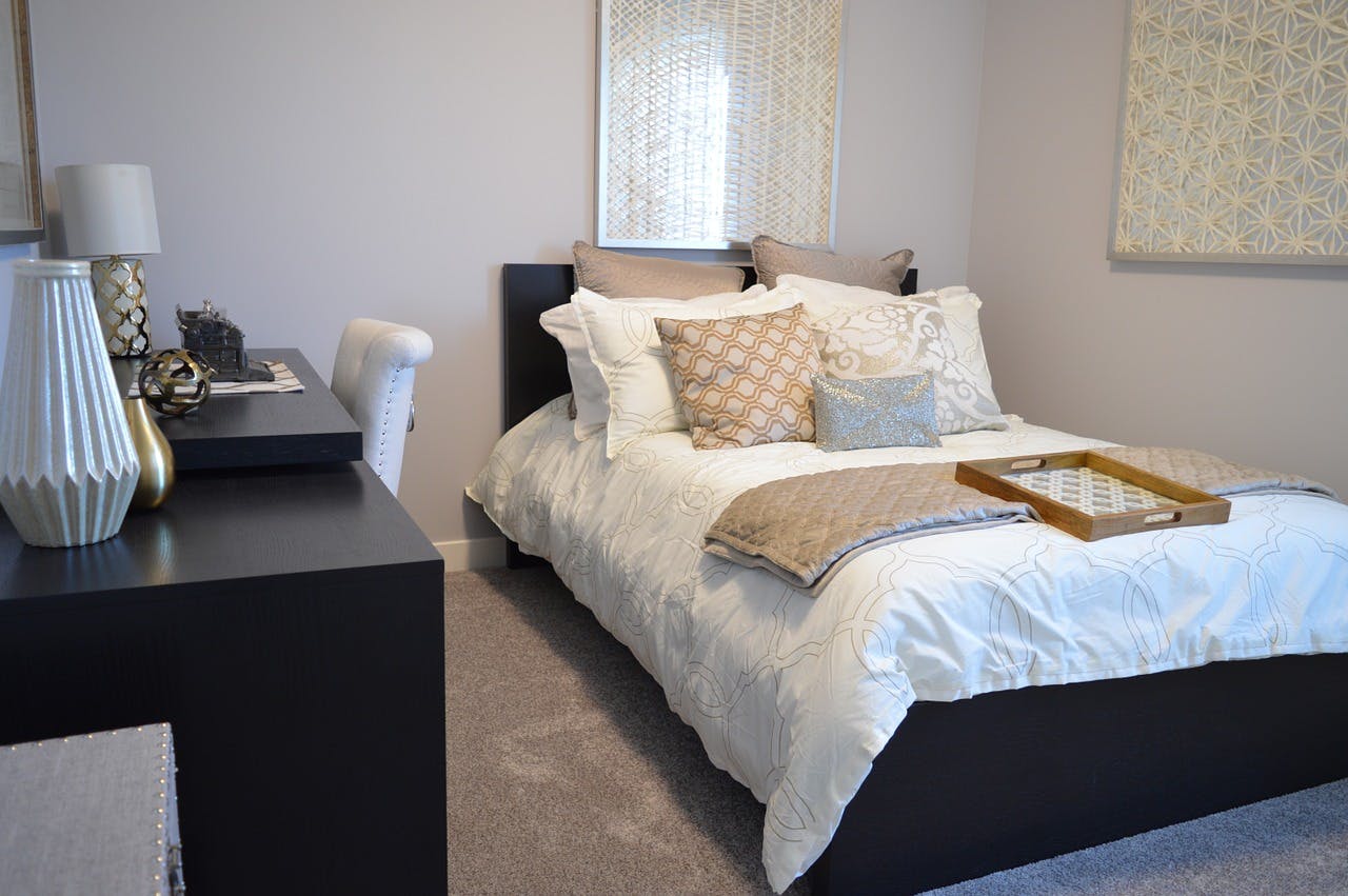Schlafzimmer mit Bett und vielen Kissen sowie einem dunklen Sideboard