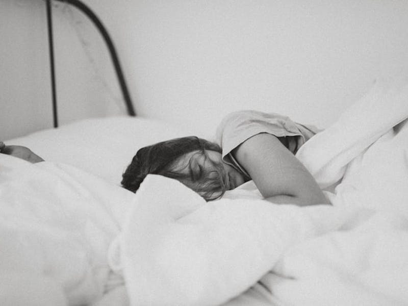 Eine Frau schläft im Bett mit der weißen Bettwäsche