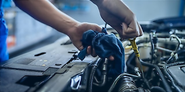 Autoreifen_wechseln_Serviceleistungen KfZ-Mechaniker schraubt etwas unter der Motorhaube