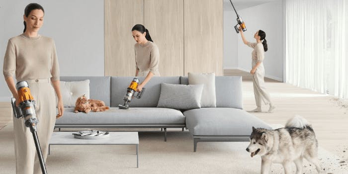 Frau saugt das Wohnzimmer in allen Ecken mit einem Dyson Staubsauger