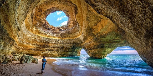 Mann schaut sich die ausgehöhlten Felsen der Algarve an