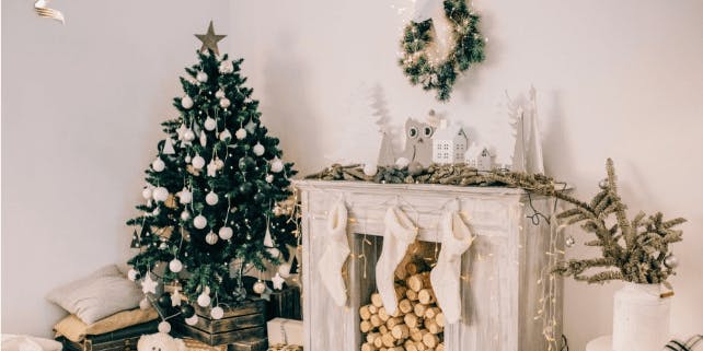 Weihnachtsbaum neben einem Kamin, alles mit Lichterketten dekoriert