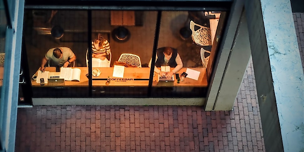 Drei Personen sitzen in einer Bar und arbeiten Drei Personen sitzen in einer Bar und arbeiten