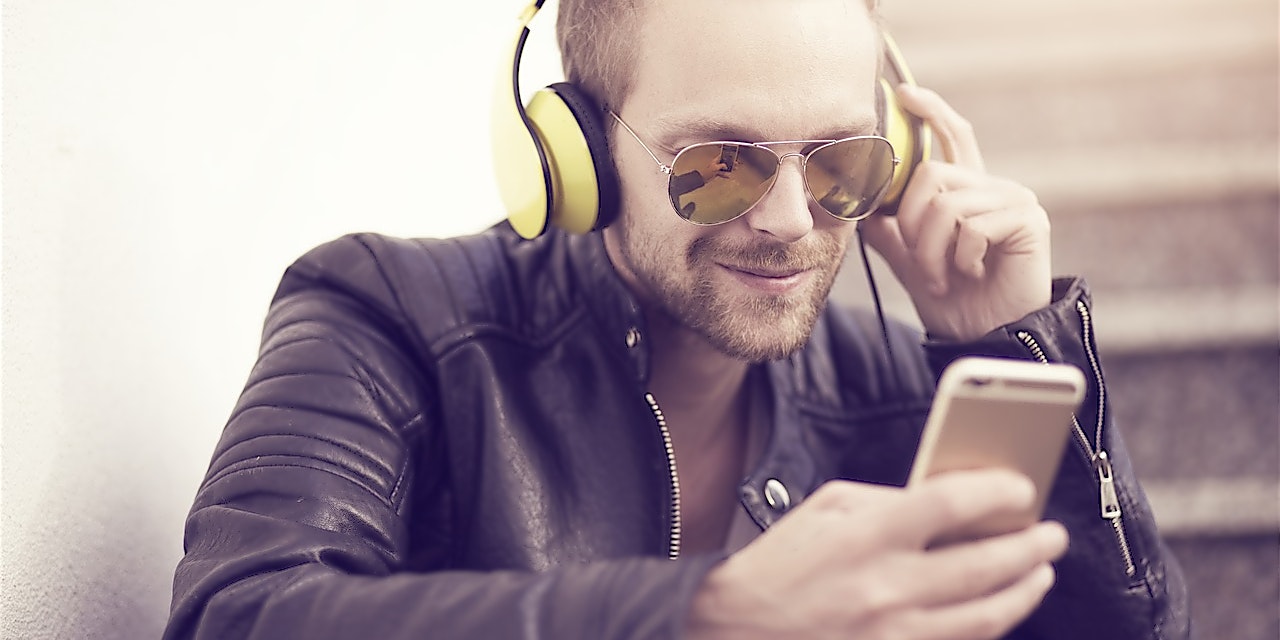 TIDAL Gutschein Mann in Lederjacke und mit Sonnenbrille auf hört Musik über sein Handy