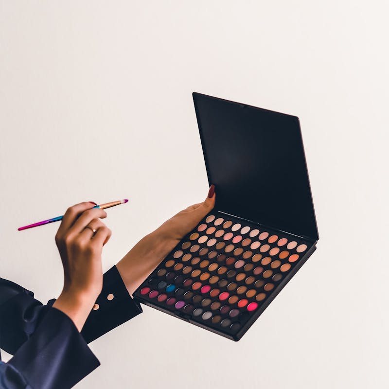 Frau hält große Make-Up Palette und Pinsel ins Bild