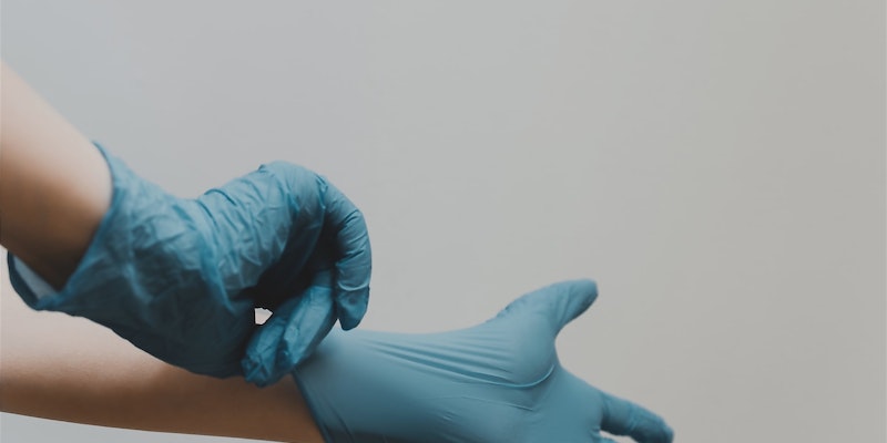 Person zieht blaue Gummihandschuhe an
