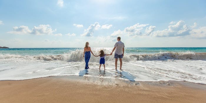Familie steht Hand in Hand am Strand