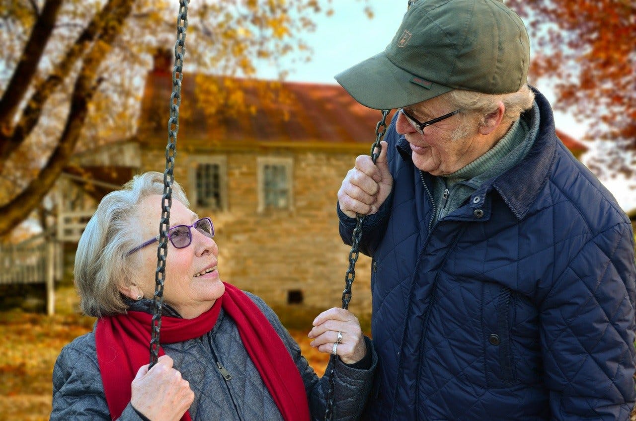 Walzvital Gutschein Oma sitzt auf einer Schaukel und schaut Opa verliebt in die Augen
