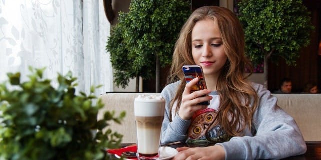 Frau sitzt mit Smartphone im Cafè Frau sitzt mit Smartphone im Cafè