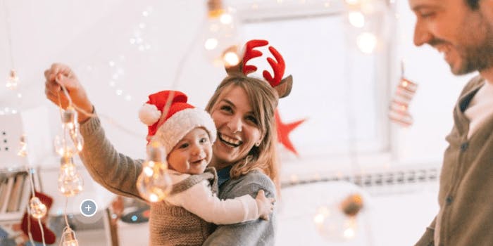 Familie mit Weihnachtsmützen dekoriert Wohnung mit Lichterkette
