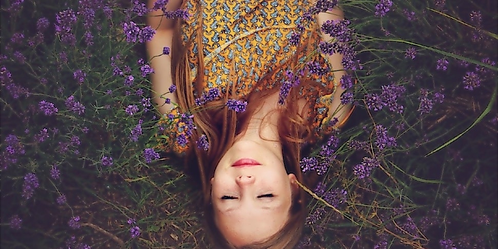 Ein Mädchen liegt mit geschlossenen Augen in einem Lavendelfeld