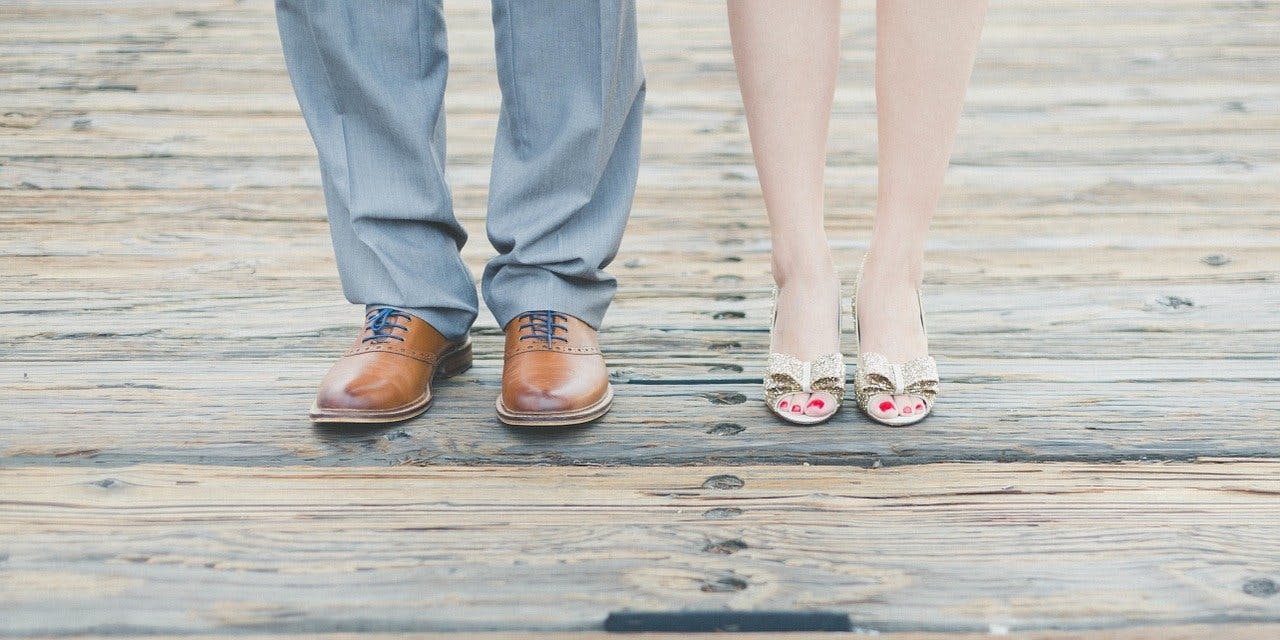 Mann in braunen Schnürschuhen aus Leder steht neben einer Frau in hochhackigen Schuhen