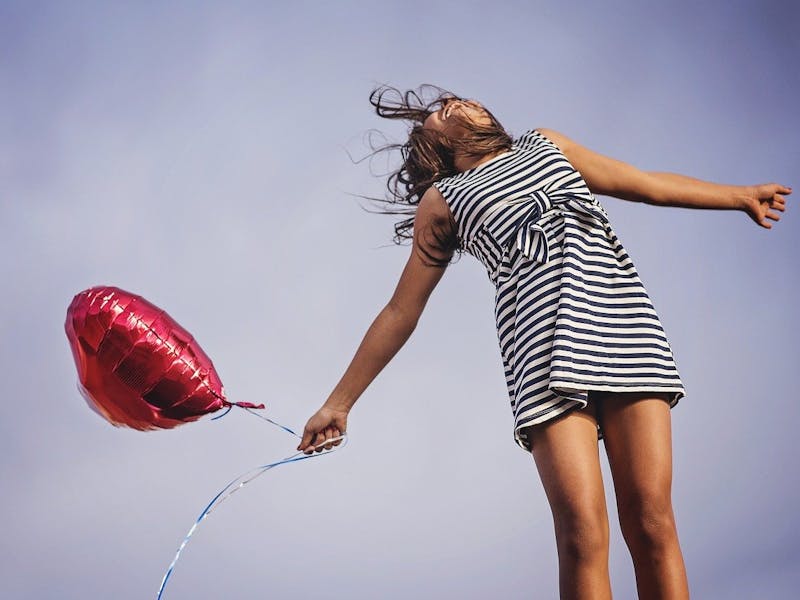 Fröhliches Mädchen mit rotem Luftballon