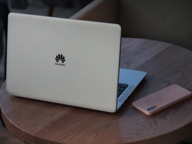 Huawei Laptop und Smartphone auf rundem Holztsch