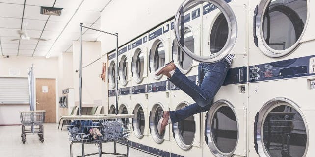 Frau klettert im Waschsalon in Waschmaschine