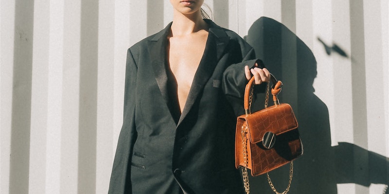 Frau in schwarzem oversize Blazer mit oranger Handtasche
