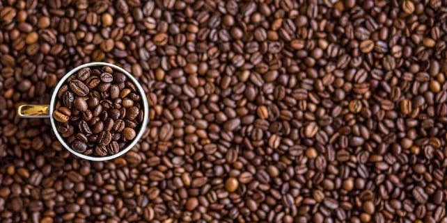 Kaffeegenuss: Tasse umzingelt von Kaffeebohnen