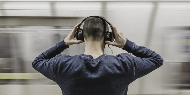 Ein Mann mit Kopfhörern vor einer Bahn