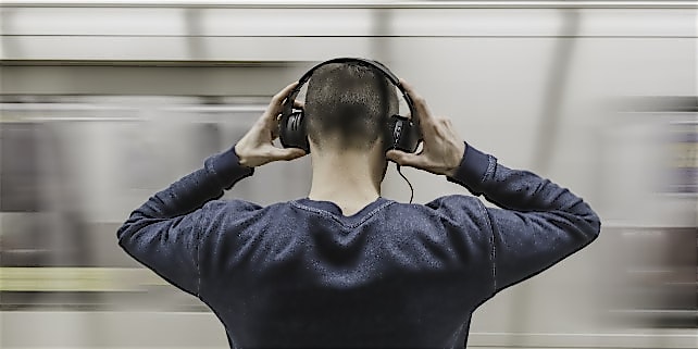 Ein Mann mit Kopfhörern vor einer Bahn Ein Mann mit Kopfhörern vor einer Bahn