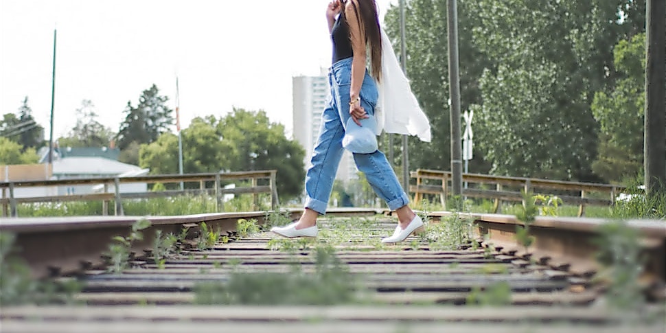 ntv-Jeans-Trends-wide Frau in weiter Jeans überquert ein stillgelegtes Gleis