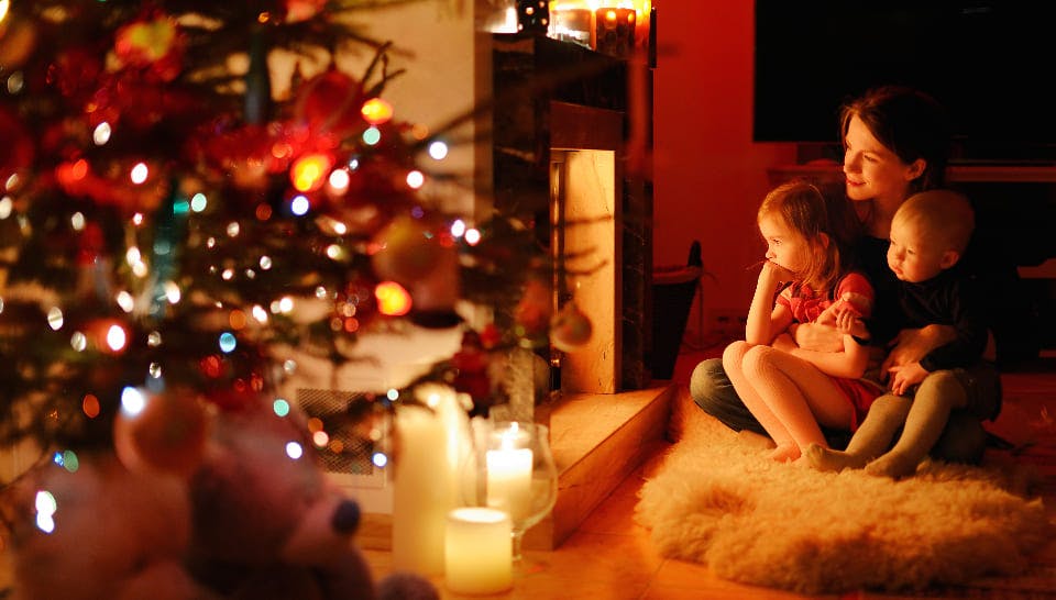 Weihnachtsbeleuchtung innen und außen: Familie sitzt vorm Kamin