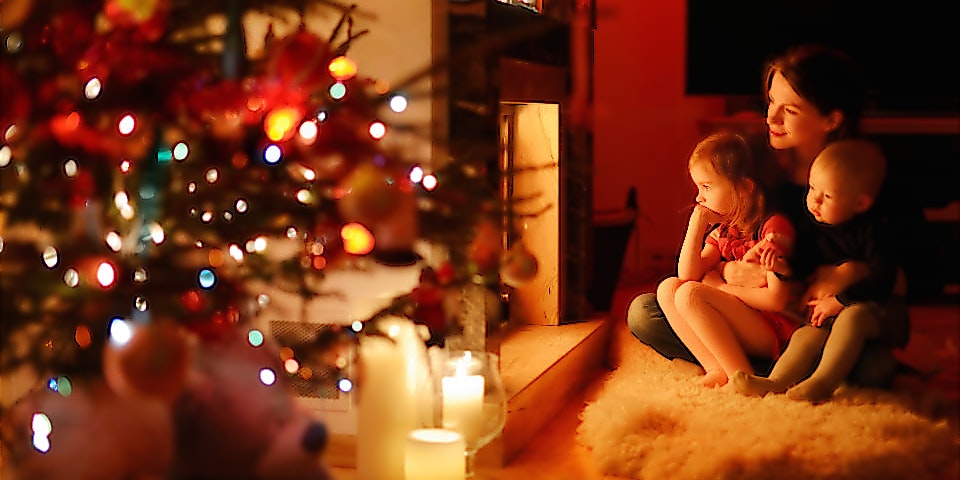 Weihnachtsbeleuchtung innen und außen: Familie sitzt vorm Kamin